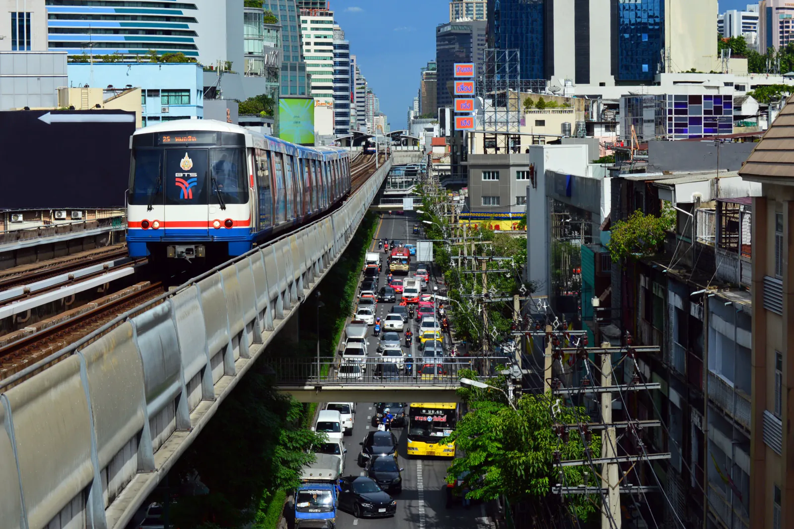 BTS Skytrain em Bangkok: transporte público e trânsito da cidade BTS Skytrain de Bangkok circulando sobre uma via movimentada entre os edifícios da cidade